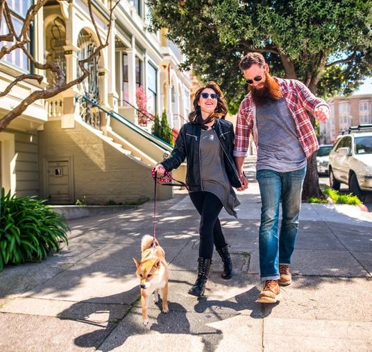 A couple out walking their dog on a city street