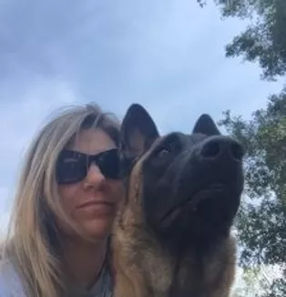 Blond Woman With Black Sunglasses Looking At The Camera While Her Dog Looks Ahead